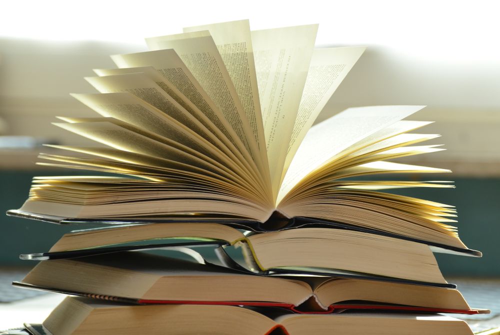 Close view of a book page margin with pencil marks and a thumb holding the corner
